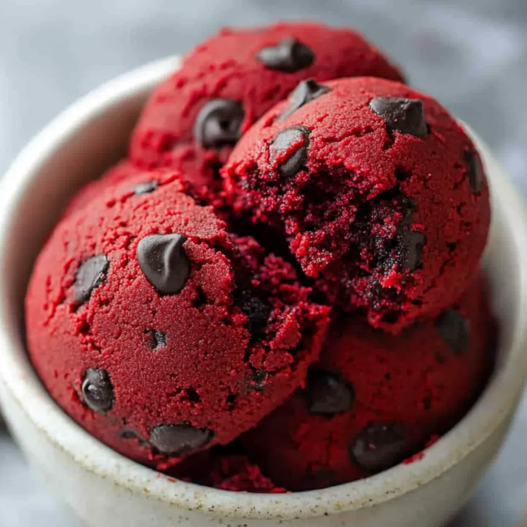 A bowl filled with deep red dough and chocolate chips.