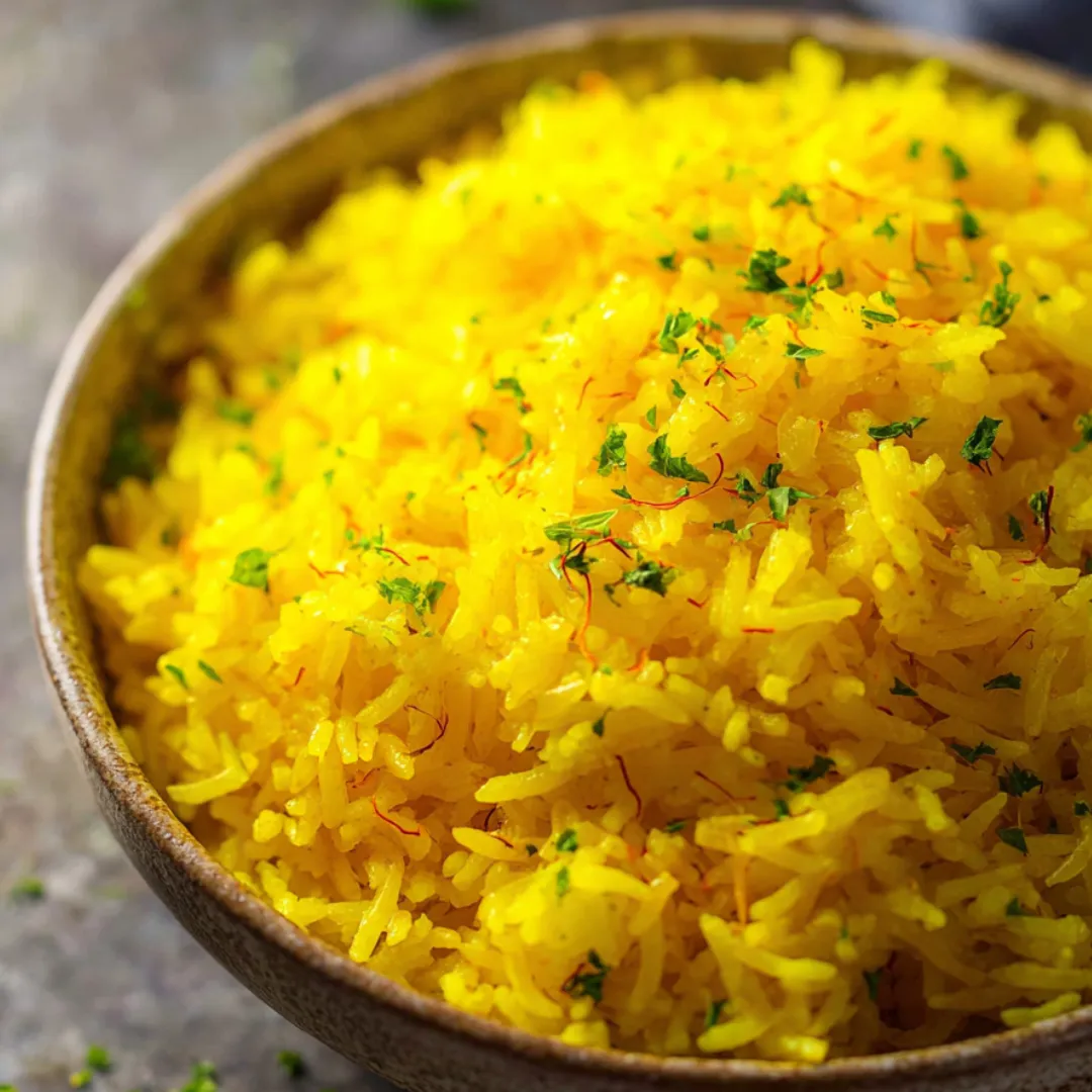 Yellow rice in a bowl topped with fresh herbs.