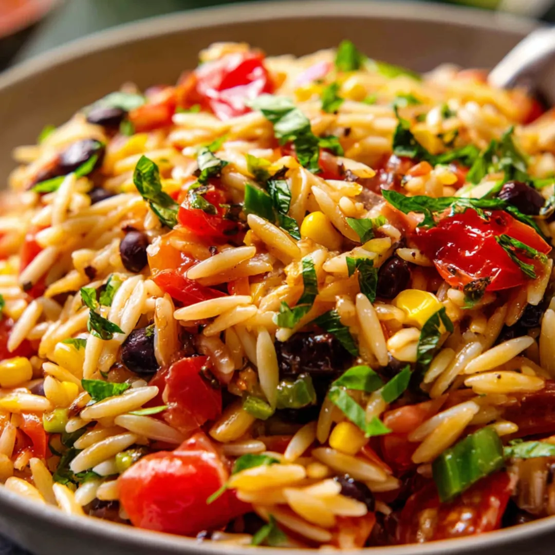 Big bowl filled with orzo, beans, fresh veggies, and tomatoes.