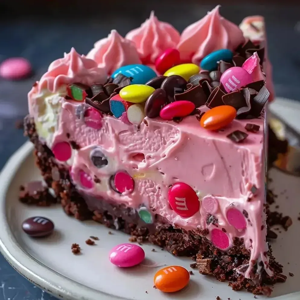 A pink cheesecake slice topped with candy and chocolate.