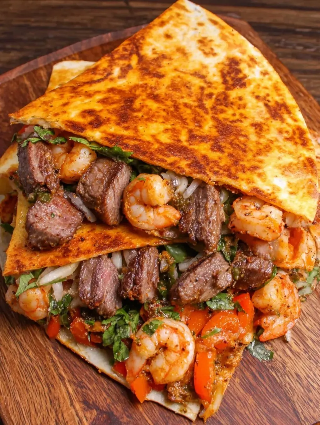 A burrito filled with shrimp, steak, and bright lettuce.
