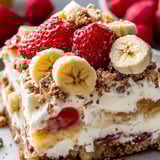 A slice of cake with bananas and strawberries on top.