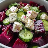 A bowl of food with cheese and cucumbers.