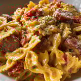 A plate of pasta with sausage and tomatoes.