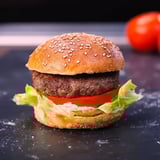 Lettuce and tomato stacked burger on a black table.