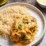 Steaming plate with chicken and rice, covered in sauce.