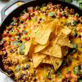 Steaming bowl of chili topped with crispy chips.