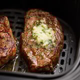 Two steaks cooking on a grill.